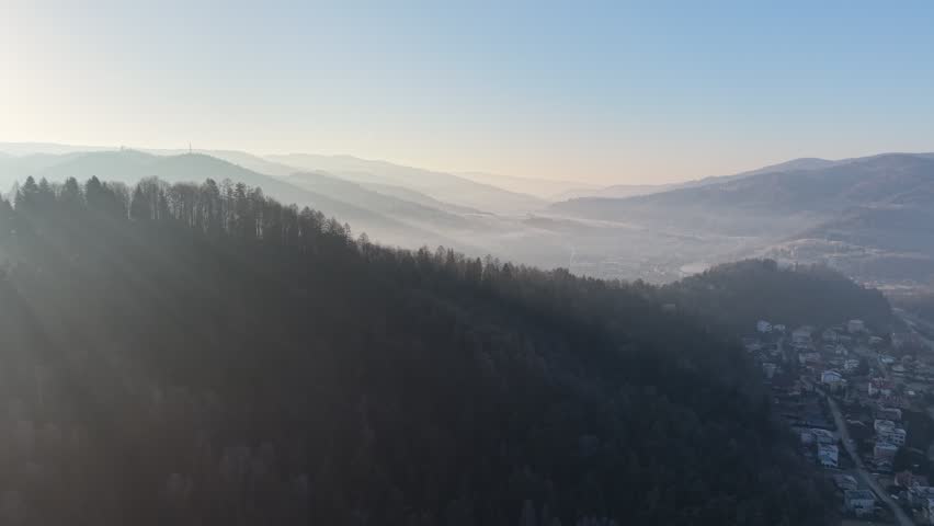 Bright sun above winter forest and grassy hills