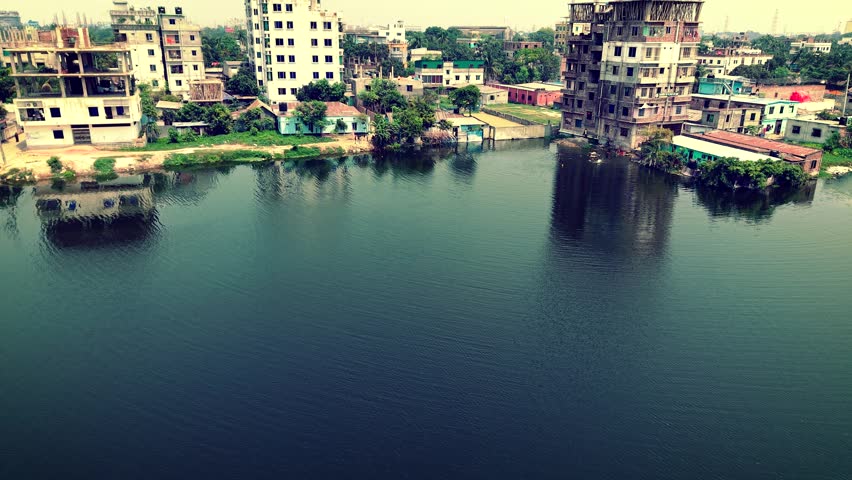 Serene Riverside Cityscape with Buildings, Water, and Greenery from Above