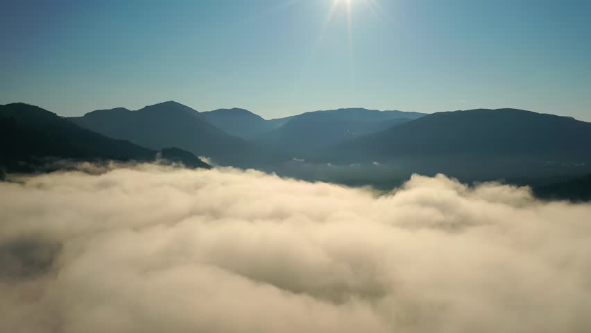 Aerial view of morning fog over mountain valley landscape.
