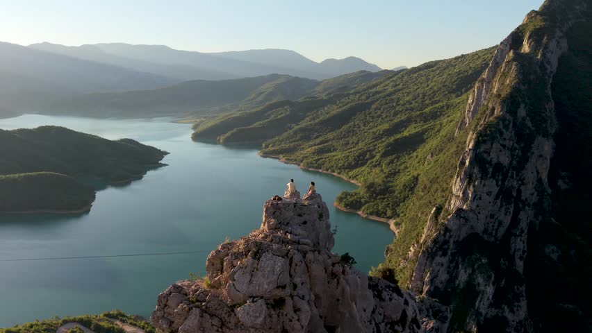 Albania boasts the stunning Bovilla Lake, A couple watching the sunrise. As the sun sets, breathtaking views emerge, creating a serene escape for travelers seeking beauty and adventure.