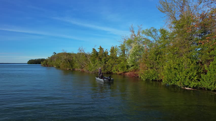 Beautiful lake Couchiching in Orillia Ontario Canada north of Simcoe Lake. Bass season opener. Motor boat with fishermen on water. Aerial view shot. Fishing boat and two anglers enjoying leisure.