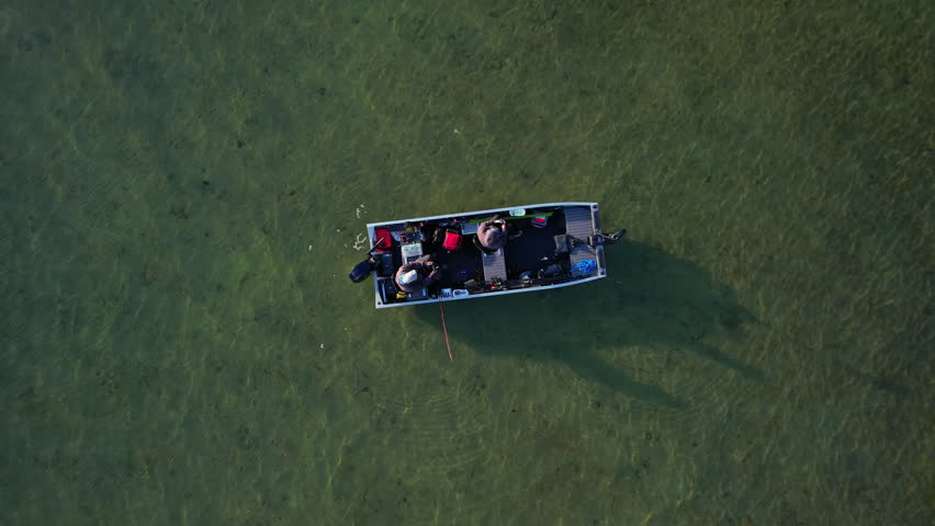 Aerial top down shot revealing epic beautiful lake Couchiching nature in Orillia Ontario Canada north of Simcoe Lake. Bass season opener. Motor boat with fishermen on water. Aerial view shot.