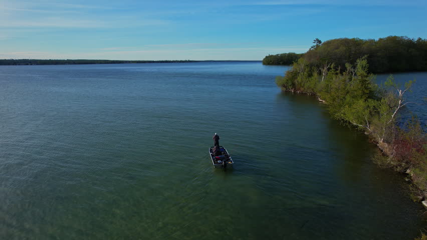 Fishing from boat and trolling at prime time sun set golden hour bass season opener in lake Couchiching Orillia Ontario Canada north of Simcoe Lake. Trolling motor on front deck. Fishing and vacation.