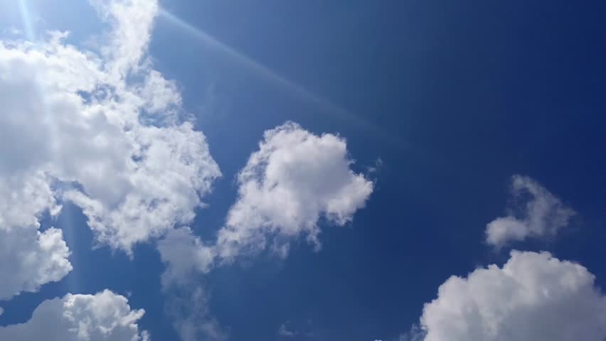 Stunning sunburst and lens flare in the blue sky with white clouds