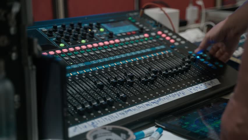 Close-up of a sound engineer adjusting controls on a professional audio mixing console. Live event production, sound engineering, audio technology, music production, and broadcasting concept.