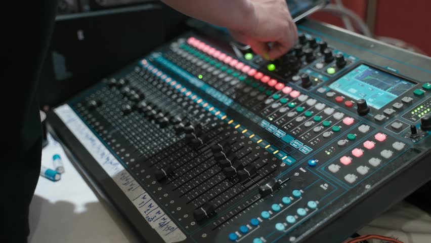 Close-up of a sound engineer adjusting controls on a professional audio mixing console. Live event production, sound engineering, audio technology, music production, and broadcasting concept.