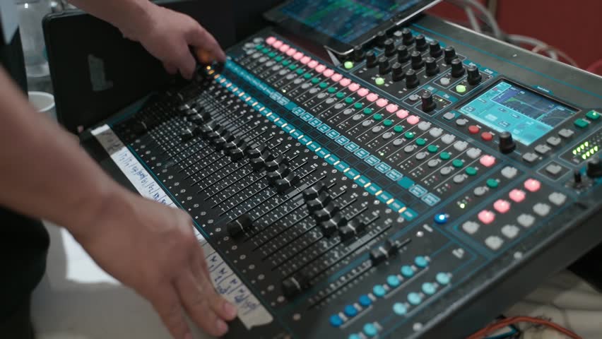 Close-up of a sound engineer adjusting controls on a professional audio mixing console. Live event production, sound engineering, audio technology, music production, and broadcasting concept.