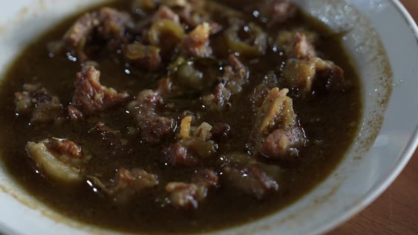 Close-up of savory beef soup in rich dark broth, featuring tender meat pieces and spices, authentic Asian comfort food footage for culinary and restaurant content.