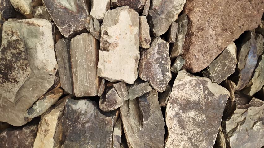 Natural stone wall texture with stacked, irregular, and flat rocks forming a rustic and solid masonry background, perfect for architectural or nature-themed concepts showing durability