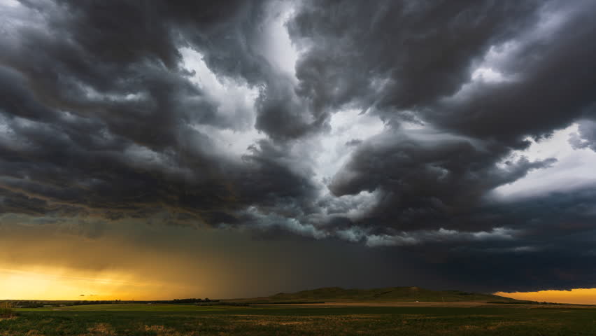 Lightning flashes within towering thunderstorm clouds as they move across the countryside, creating a dramatic rural landscape with dark skies, turbulent weather, electric atmosphere and approaching heavy rainfall conditions