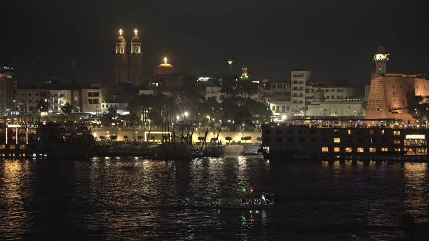 A sweeping nighttime view across the Nile River in Luxor, Egypt, showcasing the city