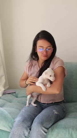 Affectionate young woman petting a cute white pinscher puppy at home