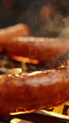 Sausages sizzling on grill, basted with sauce, fiery BBQ.