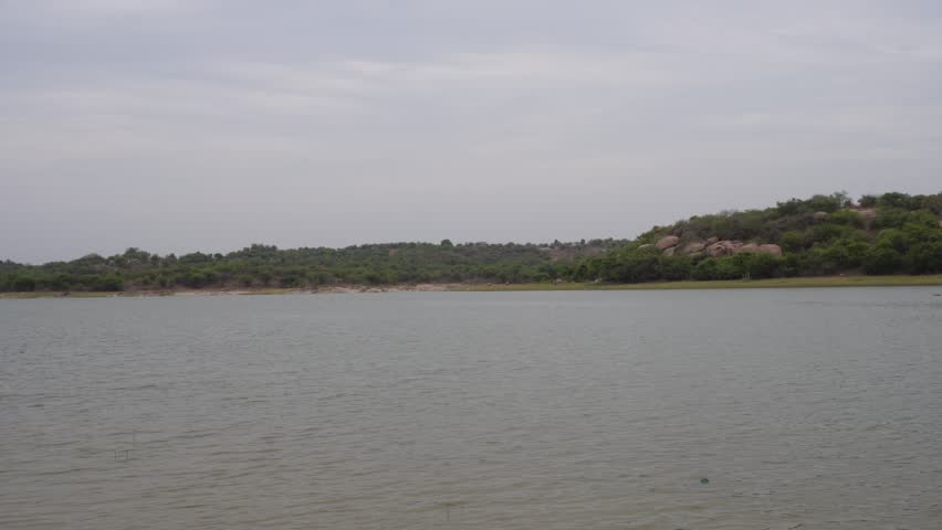 Wide freshwater lake landscape with distant hillside and calm water beneath cloudy skies