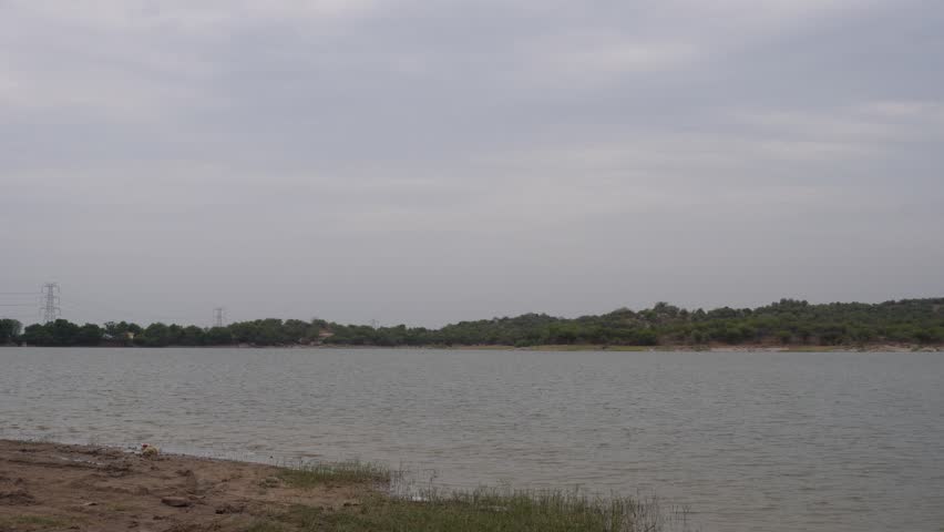 Lakeside landscape featuring shoreline terrain and calm freshwater under an overcast sky