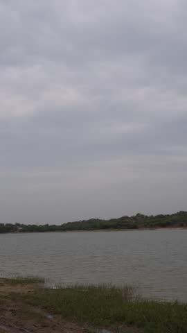 Vertical view of a freshwater lake with grassy shoreline and overcast skies