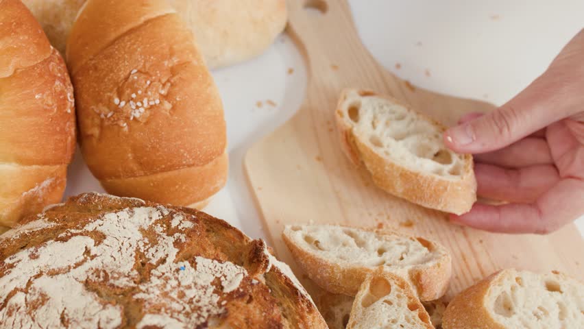 Close-up shot of butter spreading on crusty bread surrounded by sourdough and French loaves.