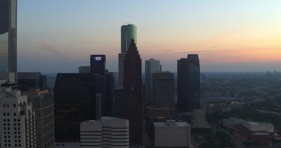 Aerial drone view of downtown Houston, Texas featuring modern skyscrapers and office towers during sunset and blue hour.