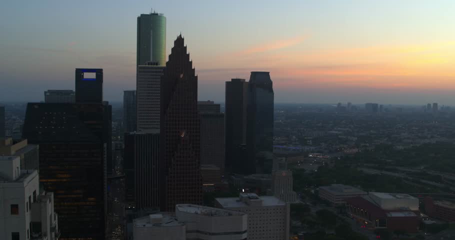 Aerial drone view of downtown Houston, Texas featuring modern skyscrapers and office towers during sunset and blue hour.