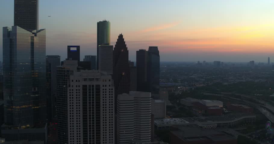 Aerial drone view of downtown Houston, Texas featuring modern skyscrapers and office towers during sunset and blue hour.
