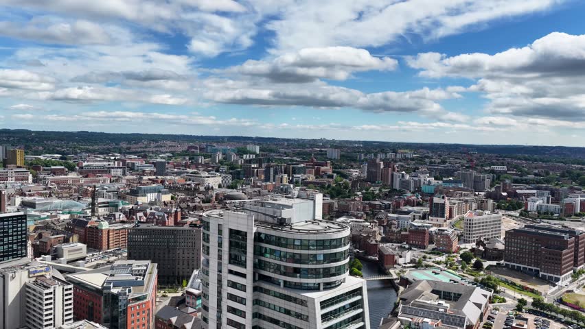 Aerial footage of the Leeds city centre featuring the Bridgewater Place apartment and modern office buildings historic warehouses and the city skyline beneath a bright summer sky with scattered clouds