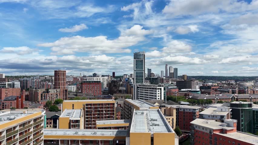 Aerial footage of the Leeds city centre featuring the Bridgewater Place apartment and modern office buildings historic warehouses and the city skyline beneath a bright summer sky with scattered clouds