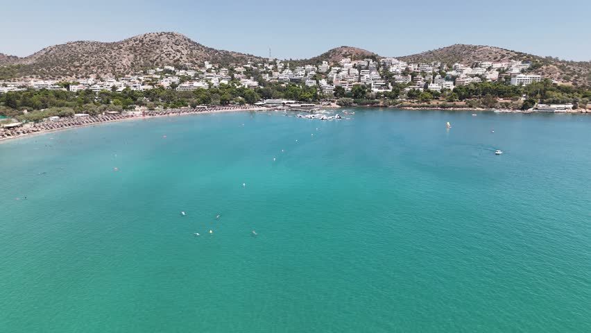 Cinematic 4K drone footage panning around to dramatically reveal the stunning Vouliagmeni Beach, one of Athens