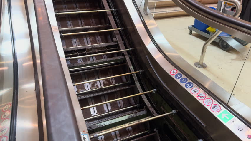 Escalator receiving maintenance while a functioning escalator and marble stairs provide alternative transportation in a subway station.