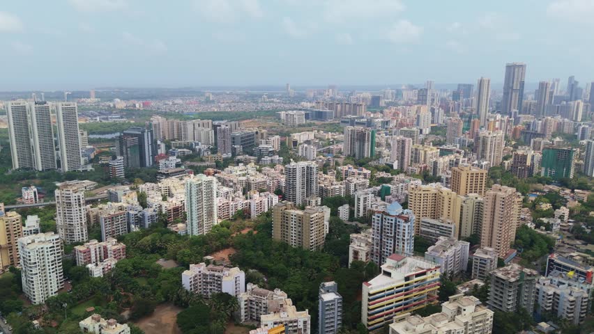 High angle view showcasing the sprawling cityscape of mumbai, india, with numerous high rise residential buildings, lush green trees, and the modern urban skyline stretching towards the horizon