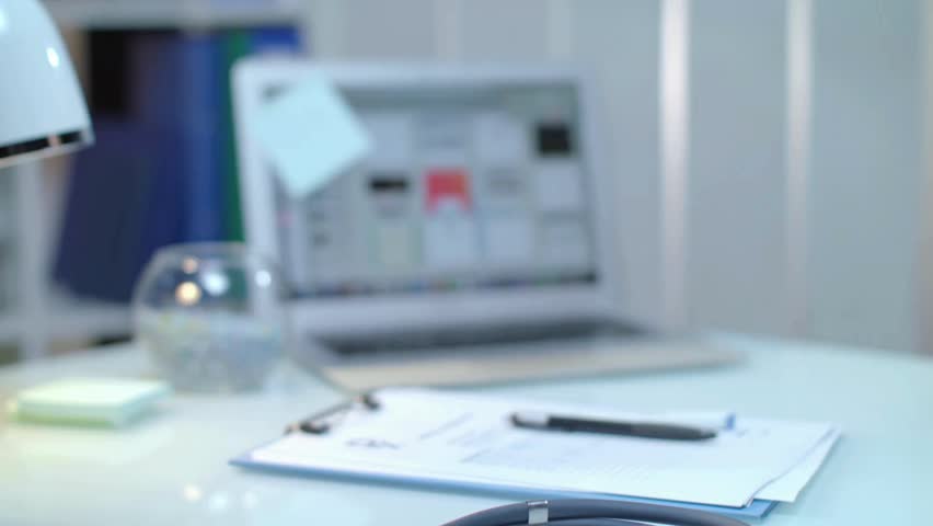 A sleek workspace showcases the intersection of medicine and technology. A laptop displays data while documents and a pen rest on a clean desk, highlighting innovative solutions in healthcare.