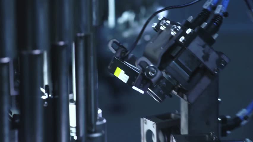 In a cutting-edge manufacturing plant, a robotic arm skillfully handles tasks on the production line during the evening shift. The environment is dimly lit but highly efficient.