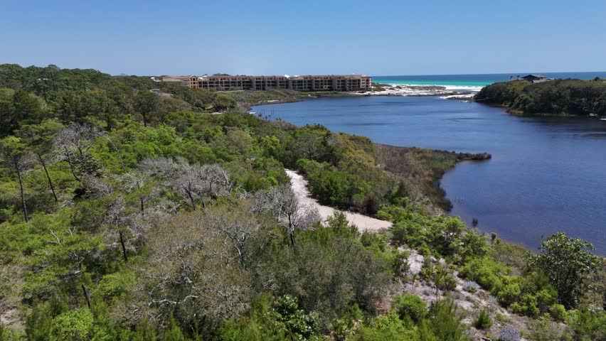 Nature overview drone shot of Big Redfish Lake environment bordered by resort properties and coastal white sandy shoreline with the Gulf of Mexico, Santa Rosa Beach, Florida, US