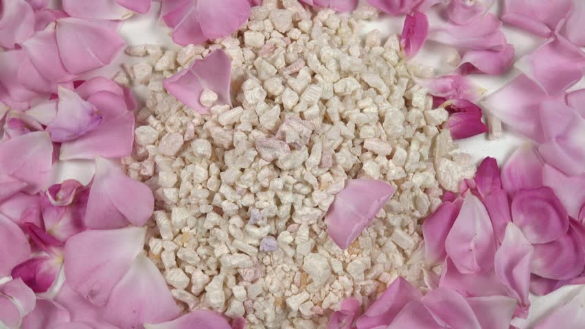 Heap of relaxing rose bath salt with use rose essential oil, fresh pink rose petals are on a white table, background, top view