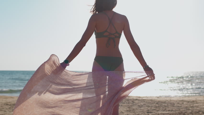 Young attractive girl with a perfect athletic figure in a bikini on a tropical summer beach.