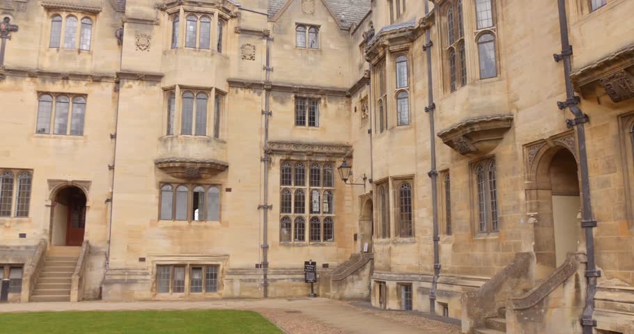 Historic stone college courtyard with arched windows and staircases in Oxford, UK