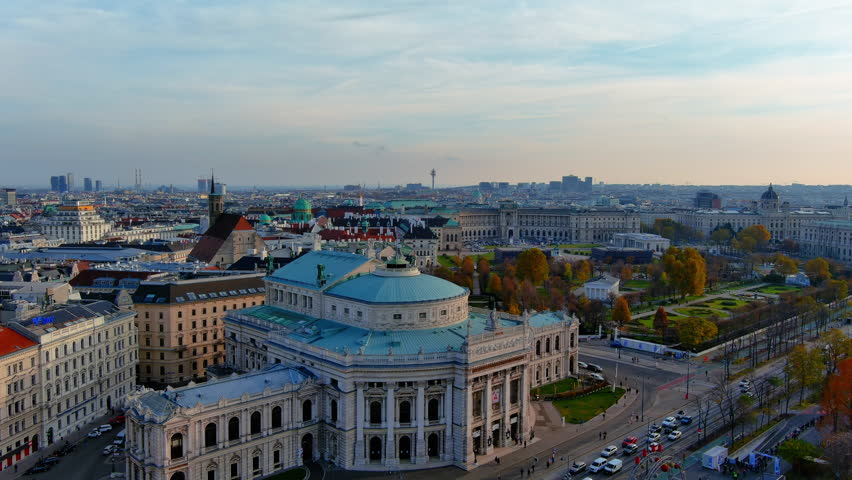 Aerial drone view of the Burgtheater, Volksgarten, and Hofburg Palace along the Ringstrasse in Vienna, Austria, autumn afternoon.