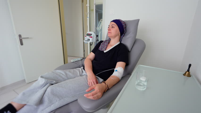 Adult woman undergoing chemotherapy treatment while seated comfortably in oncology center, cancer care environment emphasizing resilience, recovery, healing, patient support and strength throughout treatment