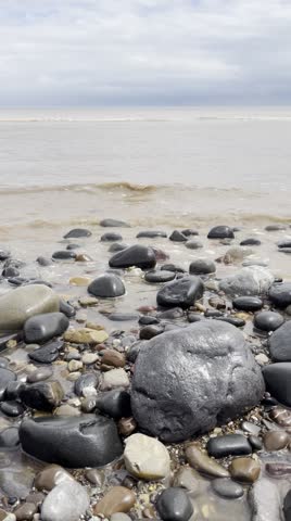 Ocean Waves Washing Over Smooth Pebbles On A Scenic Coastline Beach