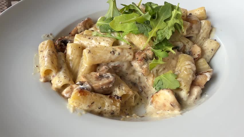 Eating pasta with chicken and mushrooms with creamy white mushroom sauce close up