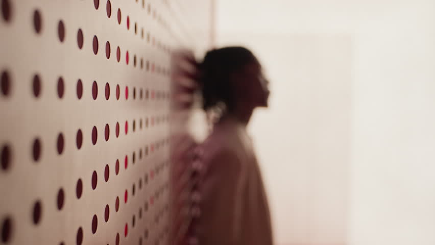 Portrait of African American young man with dreadlocks wearing glasses and suit, leaning against red patterned wall and turning to look at camera. Video is suitable for corporate diversity campaigns