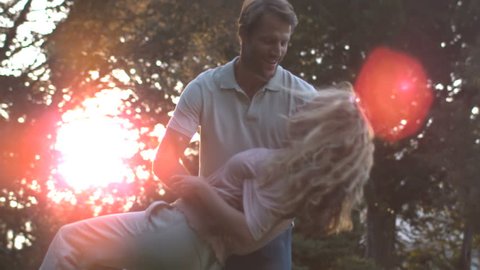Delighted couple dancing together and kissing in slow motion. summer night with lots of flare. 