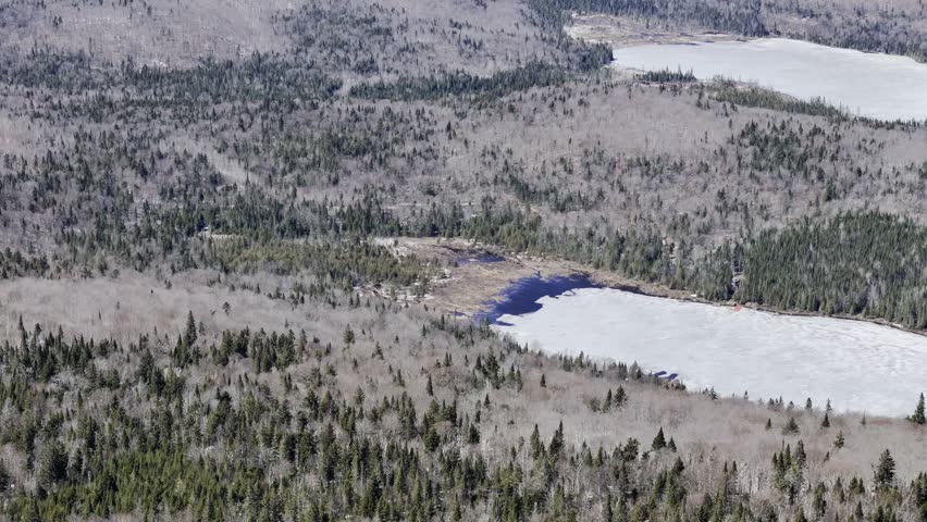 defaultAerial view of winding road along frozen lake in Quebec with forest and mountains under blue sky. g.