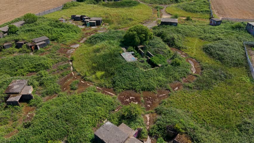 ZE1 Chadwell Heath gun emplacements from above, forward flight over central building and overgrown WWII anti-aircraft battery site with concrete pads, tracks and bunkers.