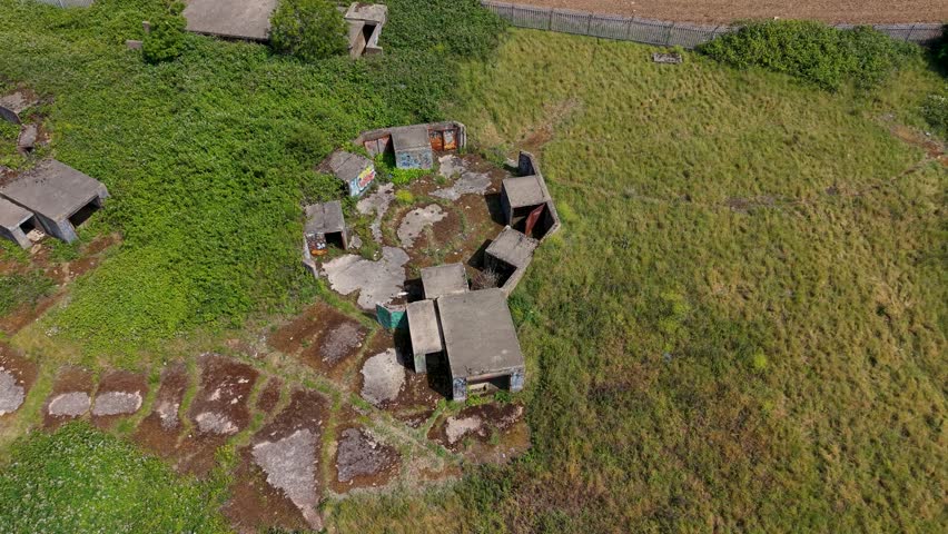 Gun Emplacements ZE1 ruins in Chadwell Heath, London. Drone descends over derelict concrete WWII anti-aircraft battery with overgrown scrub, graffiti and bunkers.