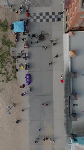 Birds eye shot of coastal promenade along Venice beach. People walking or cycling on path. Los Angeles, California, USA