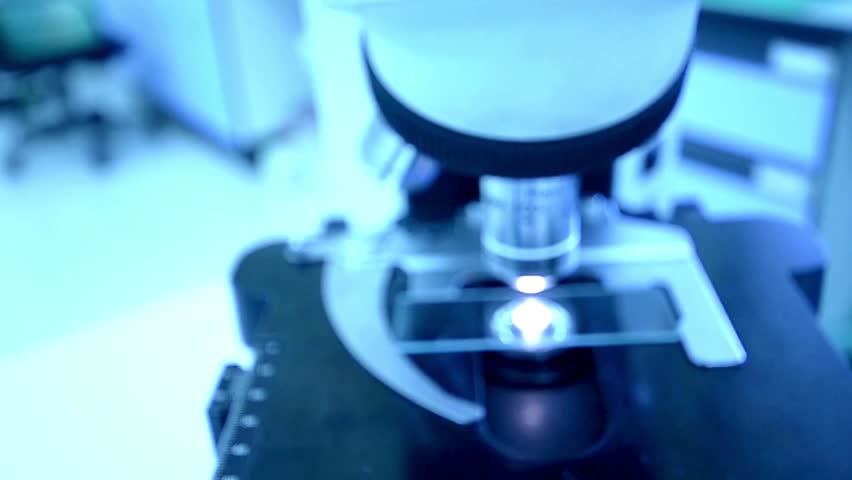 A chemist analyzes crystal formations under a microscope, researching materials for new applications in the electronics and high tech industries.