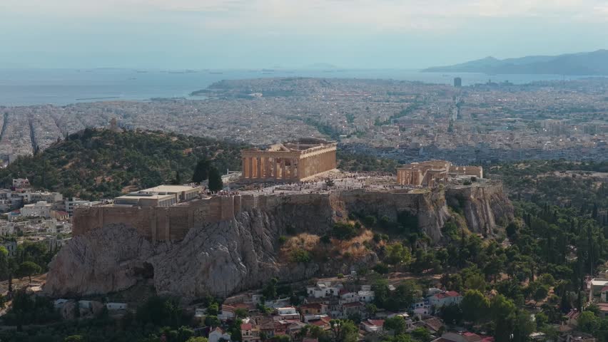 Athens cityscape featuring ancient Acropolis and Parthenon temple, an iconic landmark of Greece overlooking sprawling urban buildings and Aegean sea from a tripod