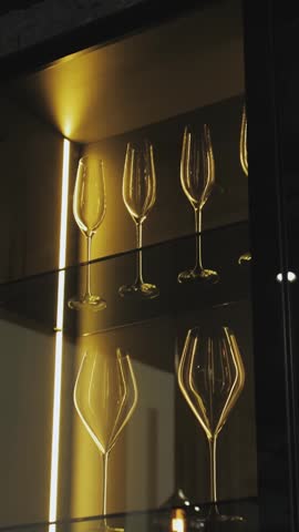 Vertical video. Row of wine glasses on glass shelf in restaurant or bar interior.