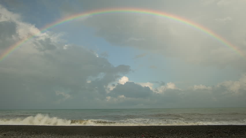 Rainbow in sky over sea.