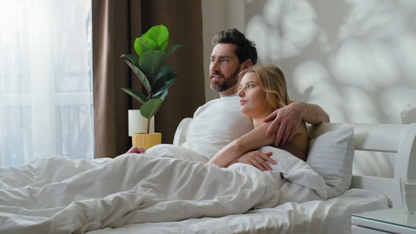 Happy family relaxed Caucasian couple cuddle talking communicating relaxing lying in bed cozy morning at home woman cuddling with lovely man talk conversation in bedroom enjoying affectionate relax